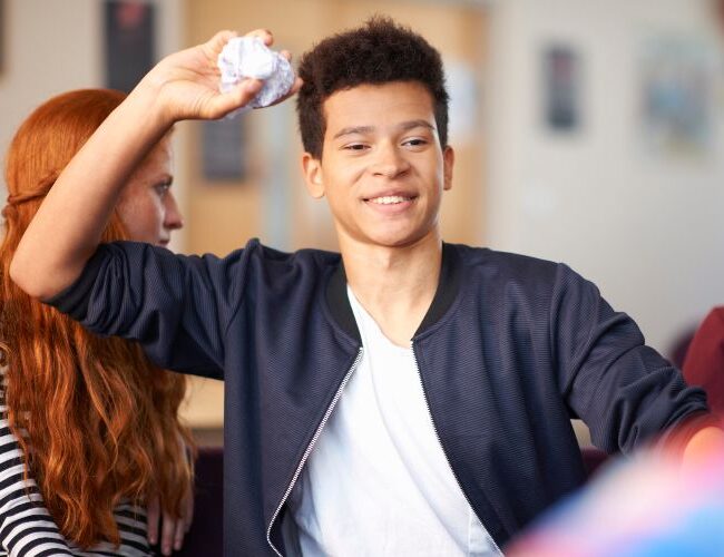 Male students throwing crumpled paper in common room